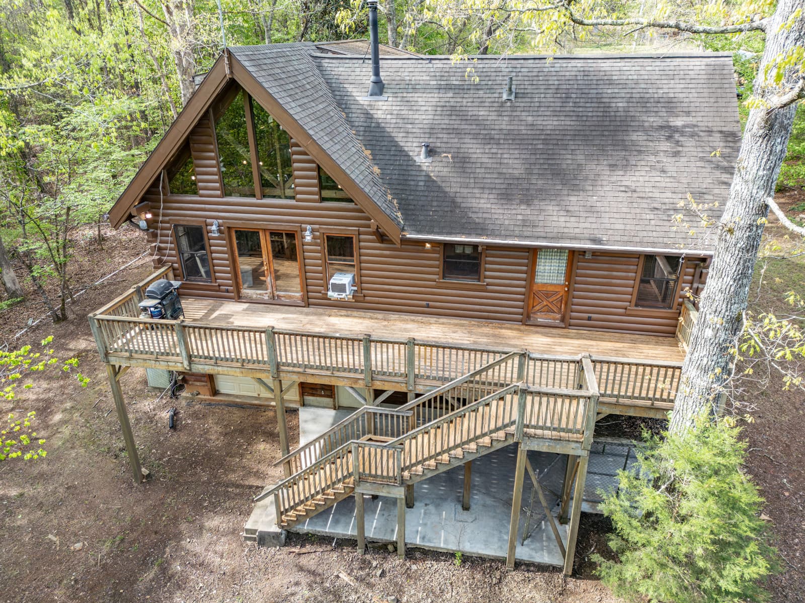 Aerial photo of three story log cabin with back deck, grill, and stairs